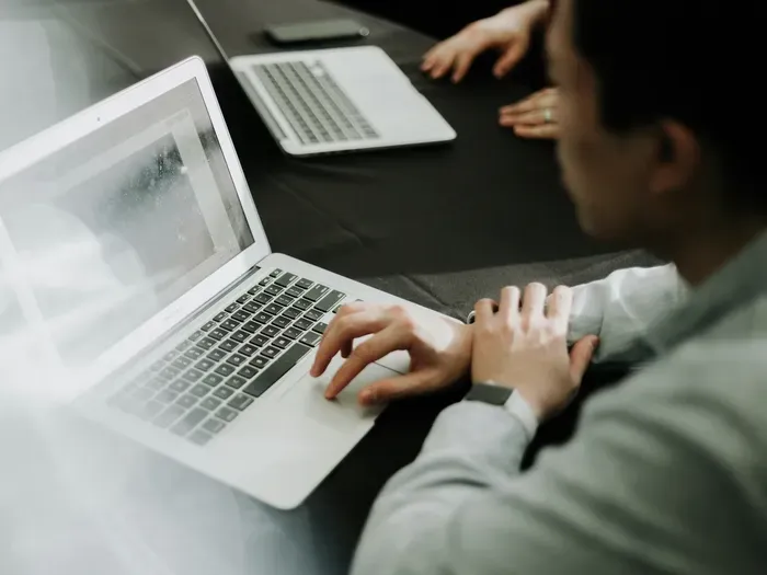 Focused man using a laptop during a meeting or office work session, representing business productivity online